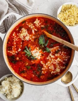 overhead photo of a large white pot of finished lasagna soup, with cheesy yum, mafalda noodles, and cheesy yum