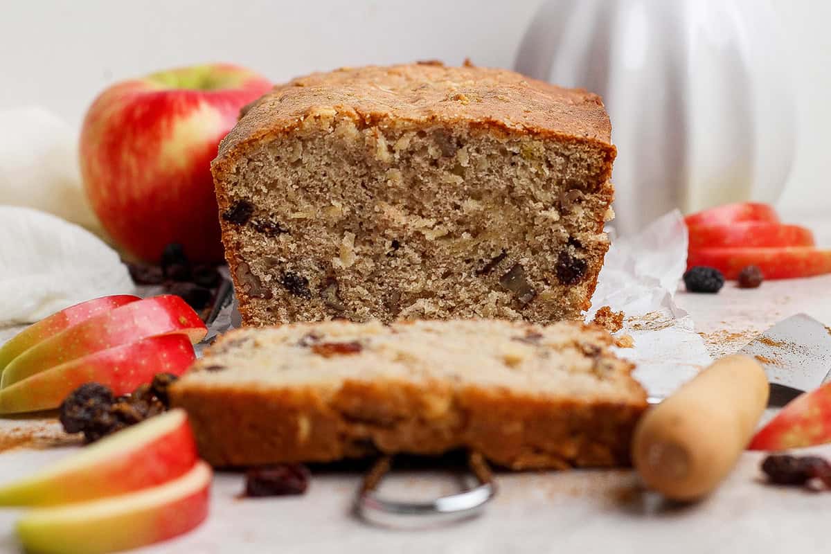 a loaf of apple bread that is sliced to show what the inside looks like, plus fresh apples