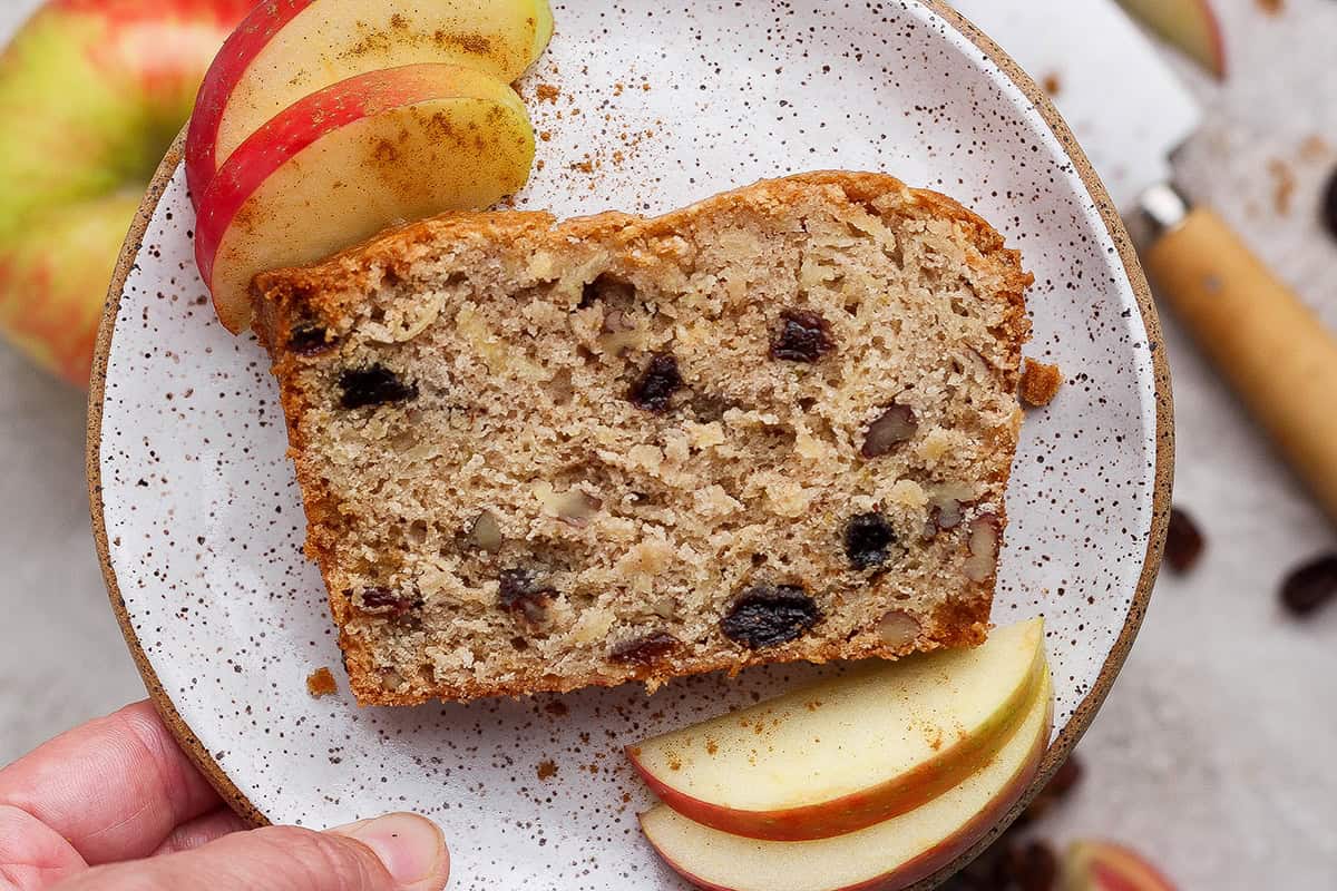 a slice of apple bread on a small plate with slices of fresh apple